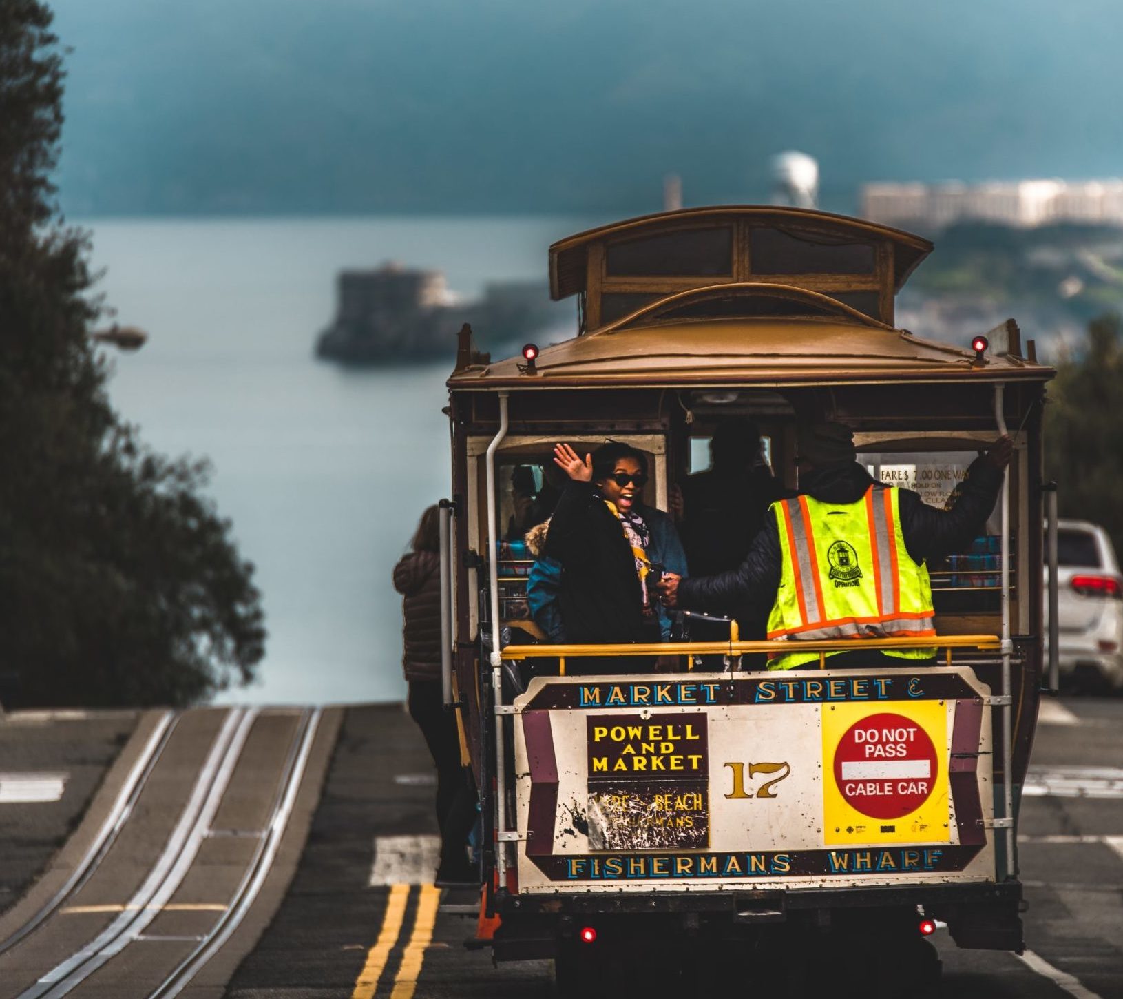 Woman waving out of the back of a San Francisco cable car