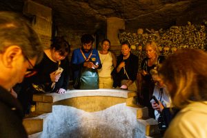Guide and group looking at tomb during Catacombs Guided Tour